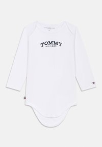 Weißer Langarm-Bodysuit aus Baumwolle, mit dem "TOMMY HILFIGER"-Logo in Dunkelblau und Druckknöpfen am Boden. Rote und blaue Akzente an den Ärmeln.