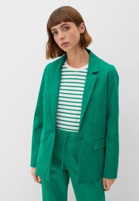 Green blazer with a notch lapel, single button closure, and two front pockets. Worn over a white shirt with green horizontal stripes.