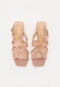 Rosa semskede sandaler med åpen tå, med kryssede stropper dekorert med rhinestones og en firkantet hæl. Spennejustering ved ankelen.
