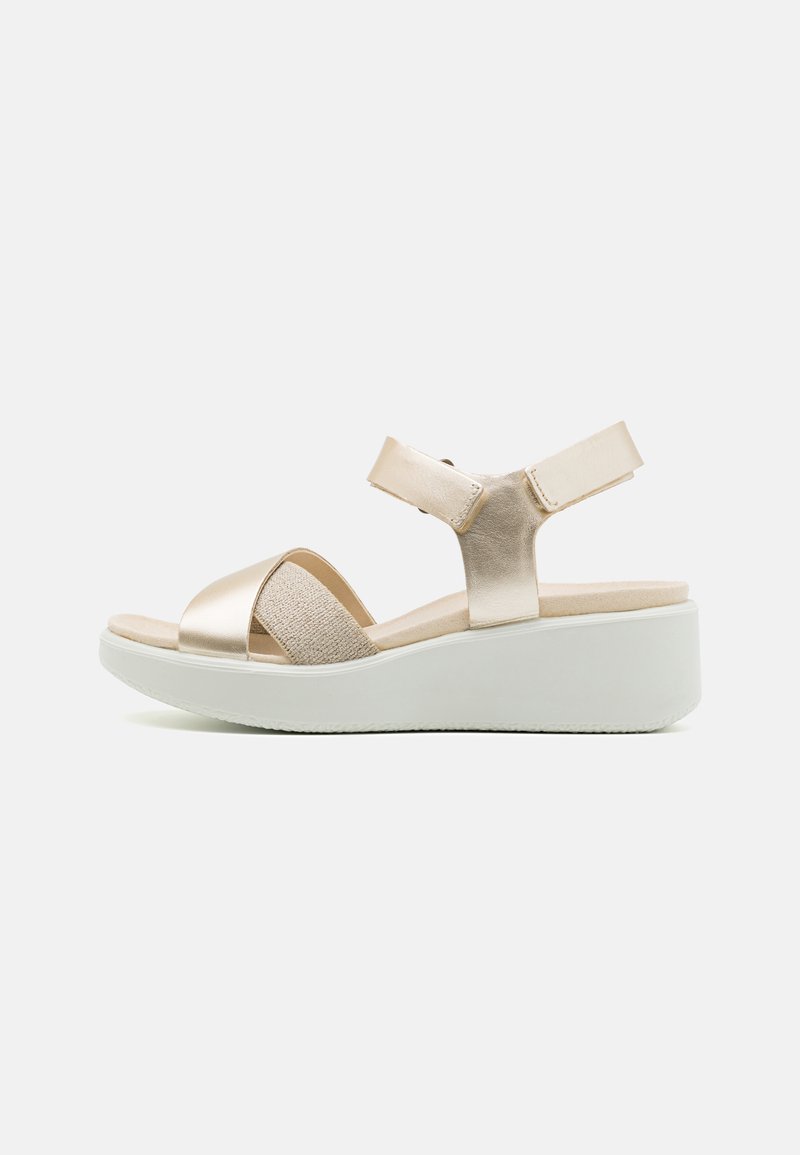 Wedge sandals with a white platform sole, metallic gold straps, textured beige insole, and adjustable ankle strap for secure fit.