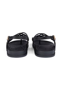 Black sandals with a woven upper, flat rubber sole, adjustable strap, and textured footbed. Minimalist design with a smooth finish.