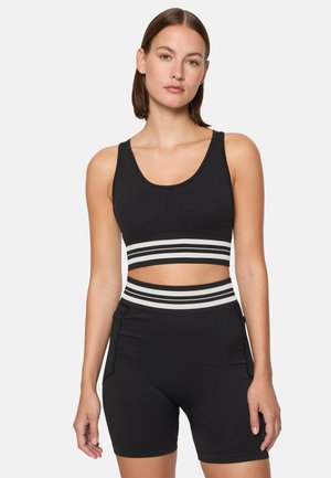 Svart träningsklädesset bestående av en crop top med vertikal ribbning och ett randigt elastiskt band, matchad med högmidjade shorts.
