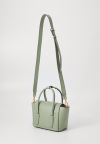 Sac à main en cuir vert avec poignées doubles, bandoulière ajustable, accents en métal doré et une forme rectangulaire structurée. Fini texturé.