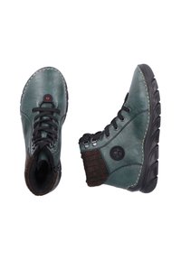Zielone skórzane botki za kostkę z teksturowanym brązowym dzianym kołnierzem, czarnymi sznurowadłami, wzmocnionymi oczkami i grubą gumową podeszwą.