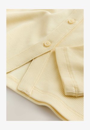 Kollane soonikkangas tekstuursete triipudega ja pehme viimistlusega. Omab ümarad, kreemikad nupud ja volditud varrukate detail.