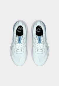 Valged spordijalatsid hingava võrkkattega pealmisel osal, helesiniste detailide ja lamedate paeltega. Keelel on ümmargune logo ning tald on sile.