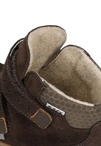 Bruine suède schoen met een zachte, gestructureerde binnenvoering. Versterkte veterogen en een tan lederen accent aan de zijkant. Casual ontwerp.