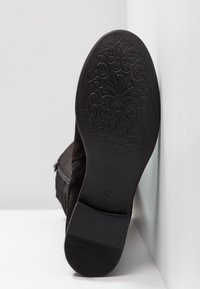 Botín de ante negro con una suela texturizada que presenta un elegante patrón floral. Detalle de cremallera lateral para poner y quitar fácilmente. Talla marcada como 37.