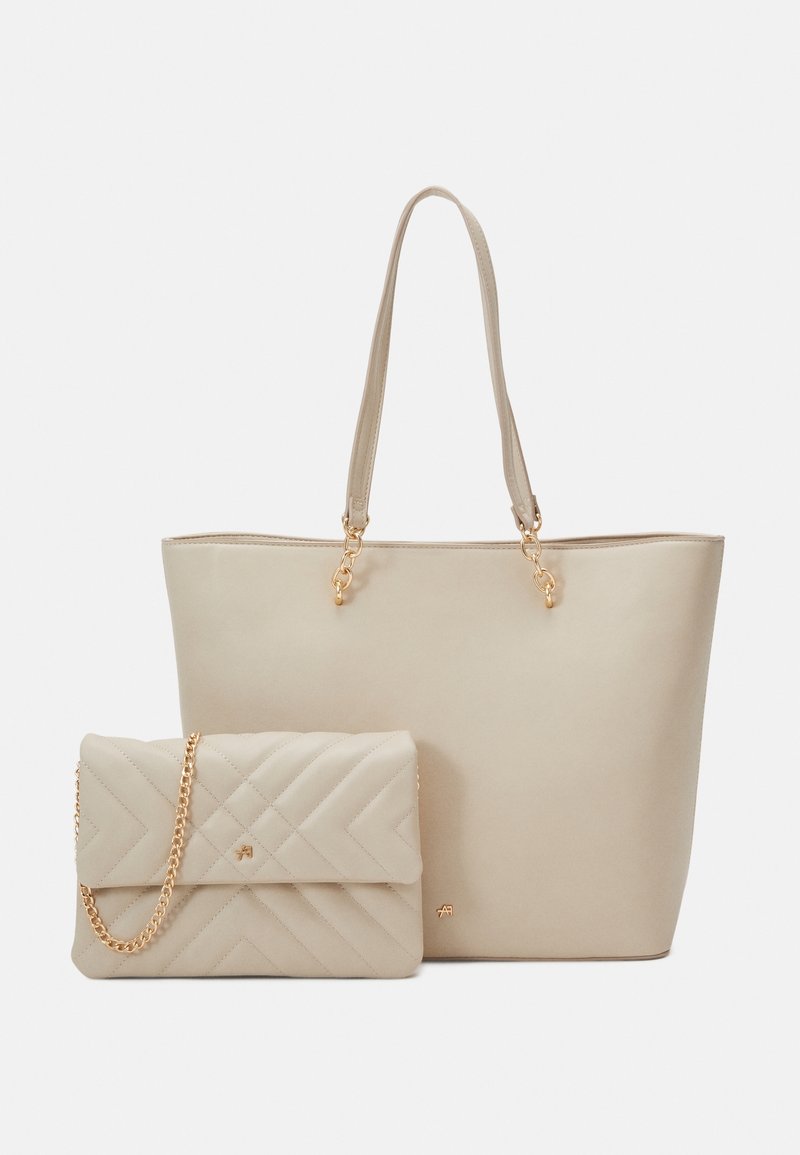 Deux sacs à main beige, un grand cabas avec double poignée et un sac bandoulière matelassé avec une bandoulière chaîne dorée, exposés sur un fond uni.