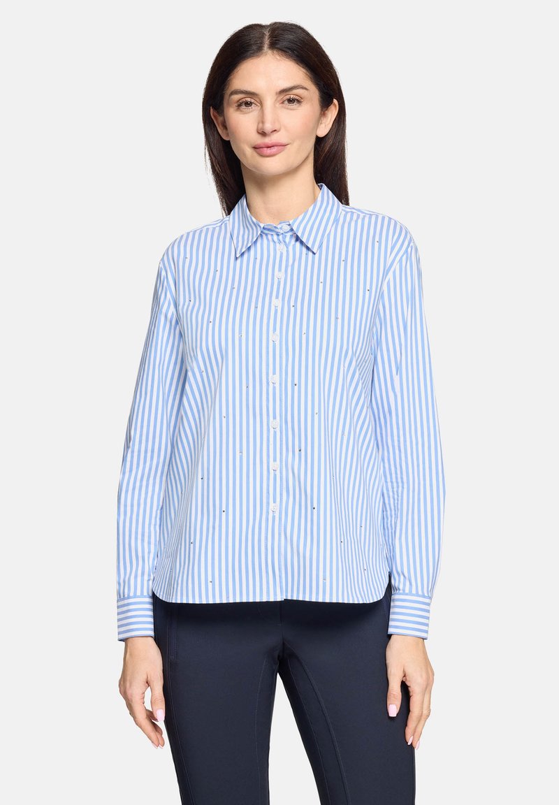 Chemise à rayures boutonnée en bleu clair et blanc avec col, manches longues et petits ornements. Tissu en coton, coupe décontractée.