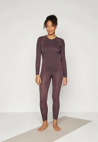 Burgundi värvi spordikomplekt, kus on pikkade varrukatega särk ja tekstuuriga legginsid. Vertikaalsed triibud heledamas toonis lisavad disainile detaili.