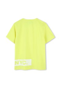 Camiseta de algodón amarilla con mangas cortas. Presenta un texto impreso en blanco "NYC." en la parte inferior izquierda. Textura suave, escote redondo estándar.
