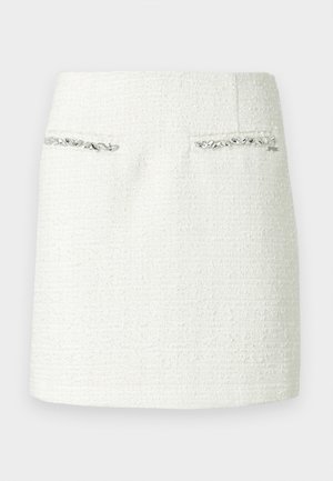 Mini-jupe en tweed blanc avec tissu texturé, comprenant deux poches avant ornées d'un bord métallique argenté. Silhouette nette et droite.
