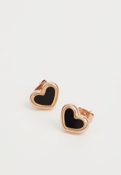 Boucles d'oreilles en forme de cœur avec un centre en émail noir et un contour en métal rose doré. Présentent une finition lisse et un fermoir à tige.