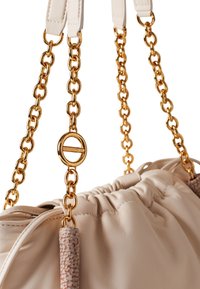 Borsa a mano in pelle beige con parte superiore arricciata, catene dorate, e dettaglio testurizzato sulla tracolla. Presenta hardware rotondo con il nome del marchio.