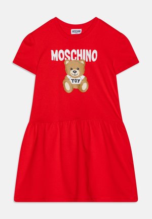 Robe en coton rouge à manches courtes, jupe à volants, avec un imprimé ourson et le texte "MOSCHINO TOY" sur le devant.