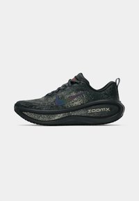 Schwarzer und grauer Nike ZoomX-Laufschuh mit schimmerndem Swoosh-Logo, dicker gepolsterter Sohle, Schnürsenkeln und Zugschlaufe vor einem schlichten weißen Hintergrund.