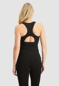 Svart sporttopp med racerback-design och ett nyckelhålsskärning, tillverkad av ett elastiskt tyg, i kombination med svarta åtsittande leggings.