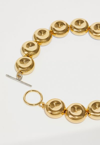 Collana di perline circolari in oro con superfici lisce e lucide. Presenta una chiusura a toggle con un attacco rotondo.