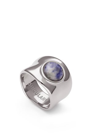 Anillo ancho de plata con acabado liso, con una piedra redonda azul y blanca en la parte superior y la palabra "SINGULARU" grabada en su interior.