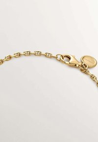 Pulsera de cadena de oro con eslabones entrelazados, cierre de langosta y un charm redondo con borde de cuerda retorcida.