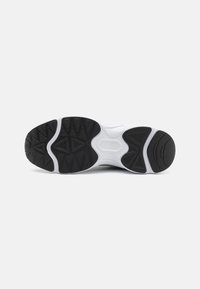 Suola di sneaker in bianco e nero con gomma testurizzata, schemi di trazione prominenti e design ergonomico per stabilità e grip.