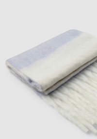 Złożony wełniany szalik w odcieniach jasnego niebieskiego i białego, z frędzlami na brzegach i miękkim, teksturowanym wykończeniem.