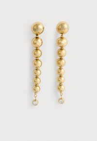 Náušnice so zlatým odtieňom, ktoré sú zložené z radu guľových korálikov s priehľadným drahokamom ako akcentom na spodnej časti. Hladký a lesklý povrch.