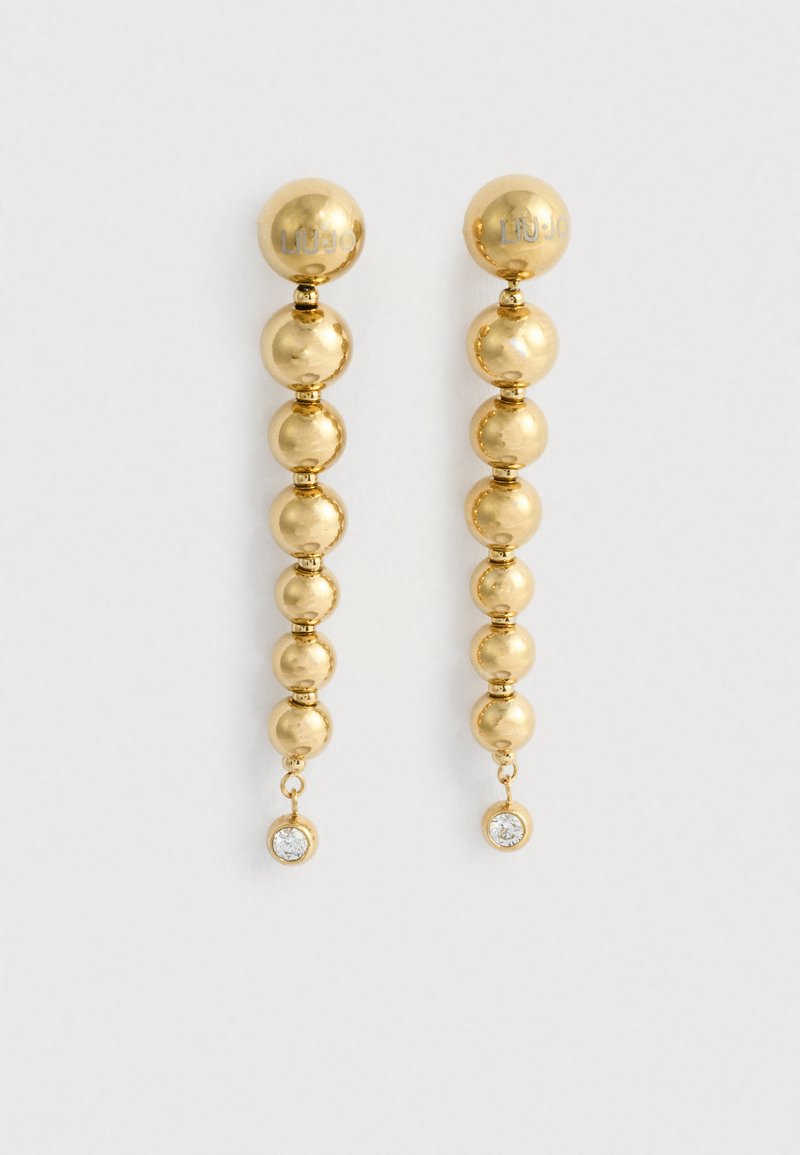 Náušnice so zlatým odtieňom, ktoré sú zložené z radu guľových korálikov s priehľadným drahokamom ako akcentom na spodnej časti. Hladký a lesklý povrch.
