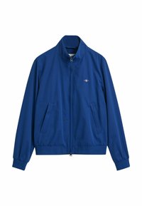 Blauwe ritsjack gemaakt van gladde stof. Heeft een hoge kraag, elastische manchetten, twee zakken aan de voorkant en een klein logo op de borst.