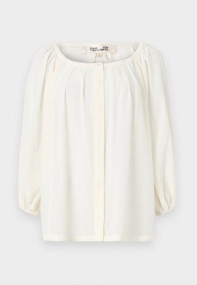 Blouse blanche avec un décolleté arrondi, un devant plissé et des manches bouffantes trois-quarts. Fabriquée en tissu léger avec une texture douce.