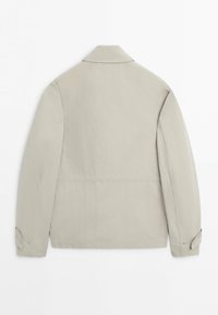 Béžová dlouhý rukáv bunda s límcem, zapínáním na knoflíky na manžetách a rovný lem, zobrazena zezadu na bílém pozadí.