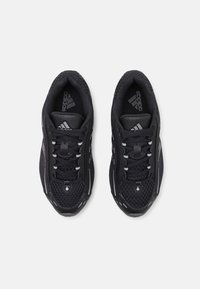 Mustat urheilukengät, joissa on verkkopinta, teksturoidut yksityiskohdat ja heijastavat yksityiskohdat. Varustettu mustilla nauhoilla ja pehmeällä sisäpohjalla.