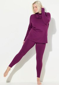 Paars langmouwtop met een kraag en bijpassende legging. De stof lijkt glad en rekbaar, met een getailleerde pasvorm.