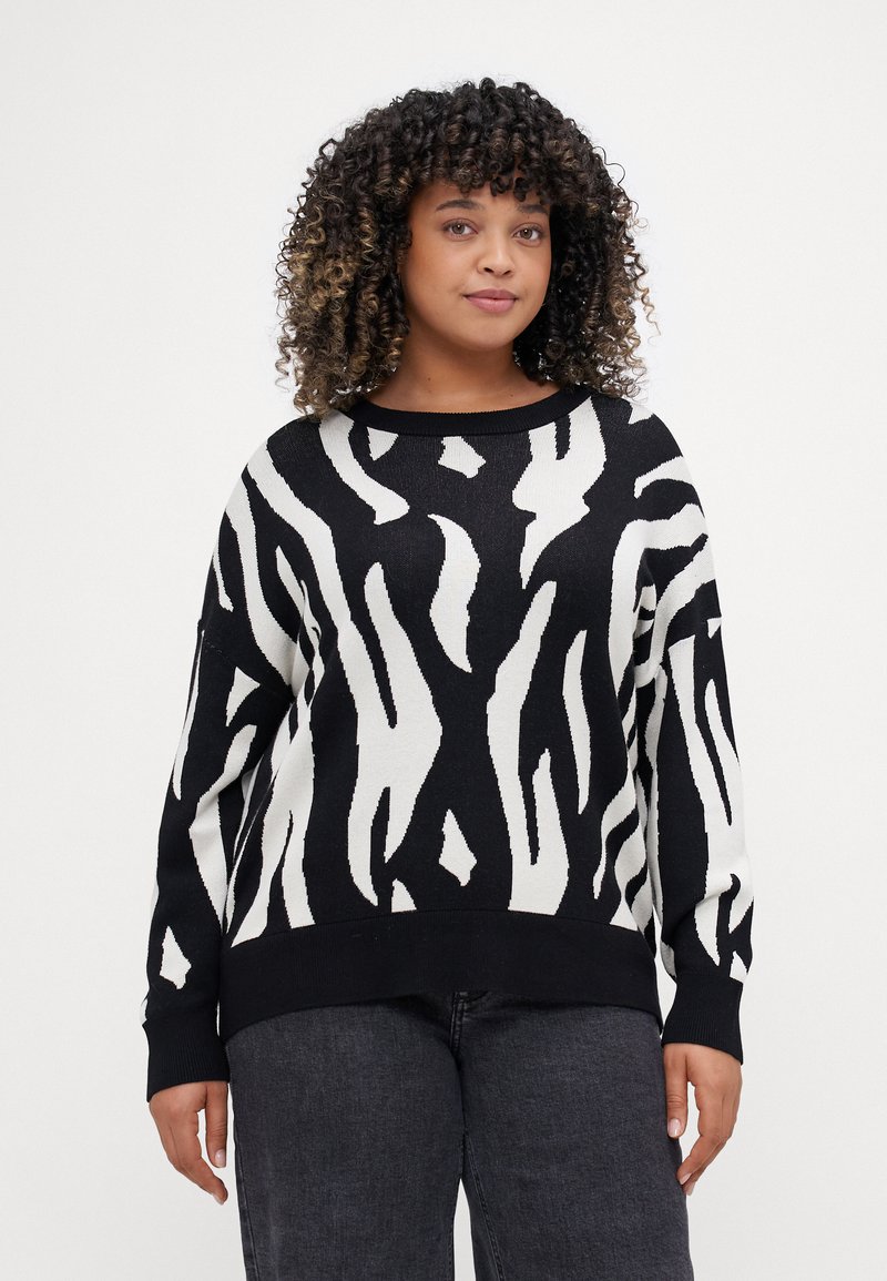 Μαύρη και λευκή ζαχαρωτή μπλούζα με σχέδιο ζέβρας, μακριά μανίκια, στρογγυλή λαιμόκοψη και λεπτομέρειες με ριμπ στο μανίκι και το τελείωμα. Μαλακό πλεκτό ύφασμα.