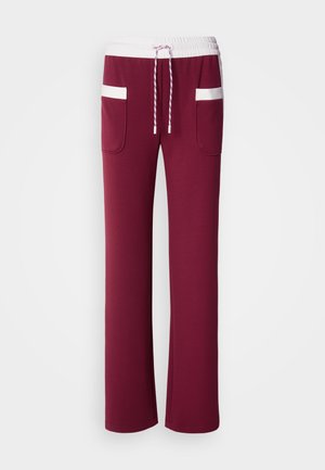 Pantaloni della tuta color marrone scuro con vita elastica bianca, coulisse e due tasche laterali con dettagli bianchi. Design morbido a gamba dritta.