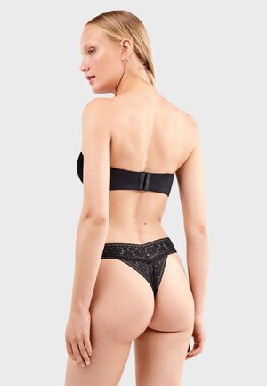 Zwarte strapless beha van een gladde stof, met haaksluiting aan de achterkant, gecombineerd met een zwarte kanten string met bloemmotieven en gegolfde randen.