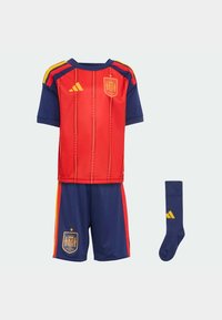 Červeno-modrý futbalový dres s krátkym rukávom s žltými prvkami, šortky s emblémom a zodpovedajúce ponožky. Vyrobené z ľahkej látky.