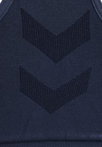 Gros plan d’un tissu bleu foncé avec deux motifs chevrons texturés vers le bas dans un ton bleu légèrement plus clair.