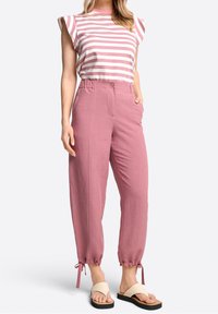 Randig kortärmad topp i rosa och vitt, kombinerad med rosa kostymbyxor med uppvikta detaljer och platta sandaler med beige rem och svart sula.