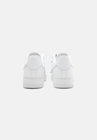 Hvite skinn-sneakers med glatt overflate, med en teksturert s�åle og preget logo på hælen. Enkel, lavtopp design.