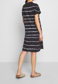 Black tie-dye dress with white horizontal stripes, short sleeves, straight cut, soft texture, and side slits for ease of movement.
