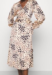 Omslagsklänning i ett mjukt, lätt material med en beige bakgrund och mörkbruna samt persikofärgade leopardfläckar. Långa ärmar med knytmidja.