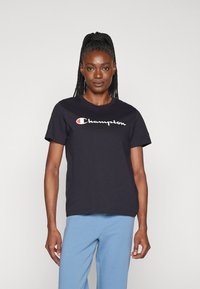 Černé bavlněné tričko s krátkými rukávy, s bílým a červeným logem "Champion" na hrudi. Jednoduchý, klasický design.