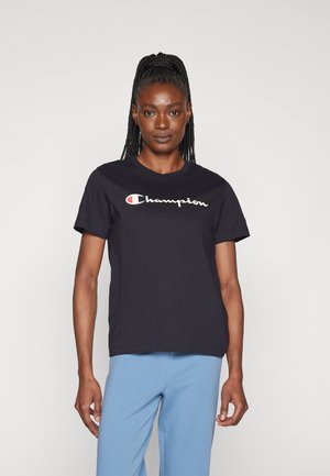 T-shirt in cotone nero con maniche corte, caratterizzato da un logo "Champion" bianco e rosso sulla parte frontale. Design semplice e classico.
