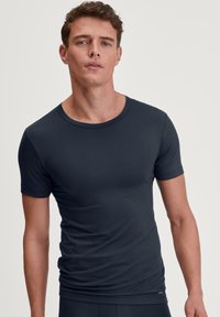 Donkerblauwe T-shirt met korte mouwen, aansluitend design, gladde textuur, ronde halslijn, minimale branding zichtbaar nabij de zoom, klassieke stijl.