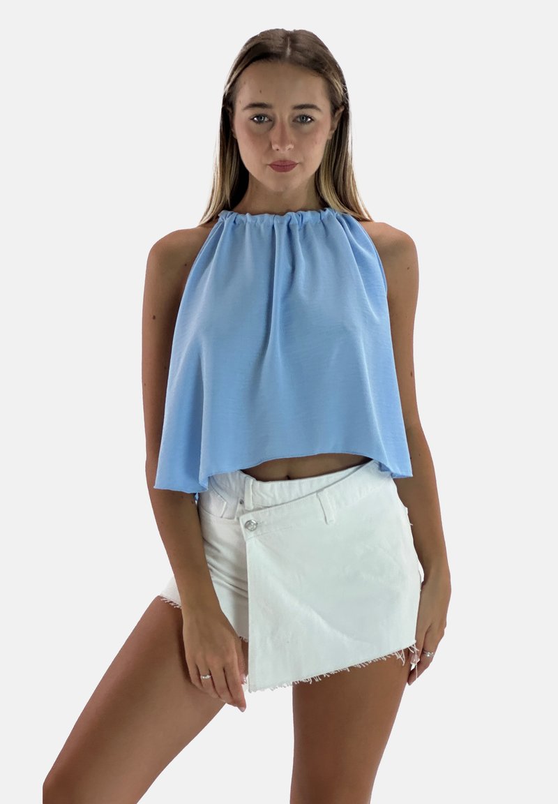 Top corto azzurro chiaro con scollo a halter e plissettature, abbinato a una mini gonna in denim bianca con bottone laterale e orlo sfrangiato.