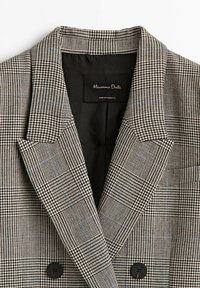 Blazer à motif pied-de-poule noir et blanc avec revers crantés et deux boutons noirs, étiqueté Massimo Dutti, fabriqué au Portugal.