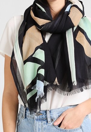 Écharpe à motifs noirs, beiges et menthe, fabriquée en tissu léger avec des bords frangés. Drapée librement autour du cou.