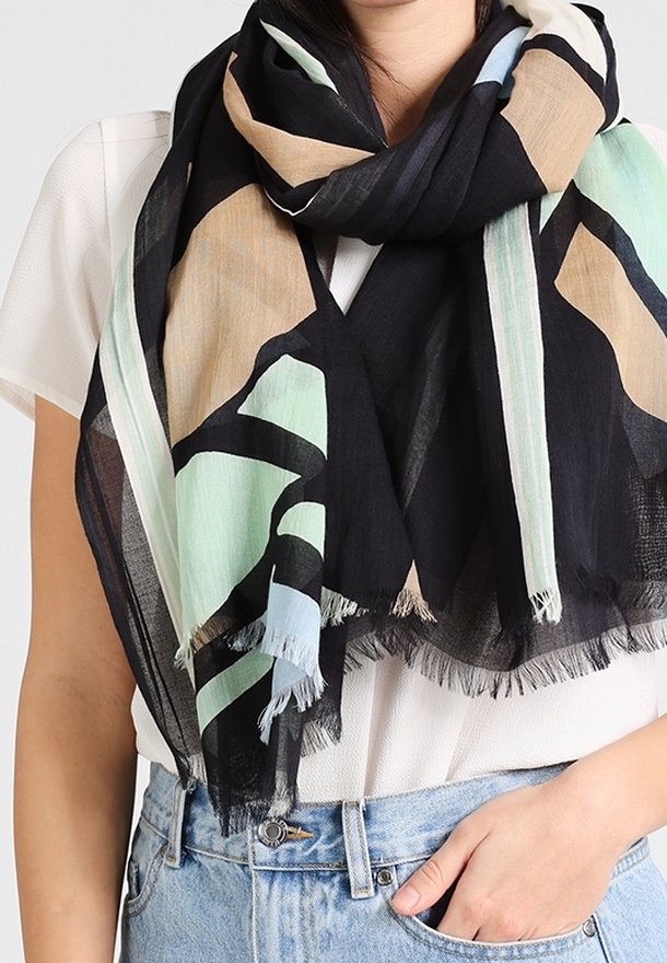 Écharpe à motifs noirs, beiges et menthe, fabriquée en tissu léger avec des bords frangés. Drapée librement autour du cou.
